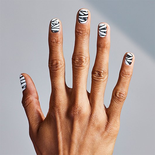 outstretched medium skin hand with short nails featuring black & white mummy nail art 