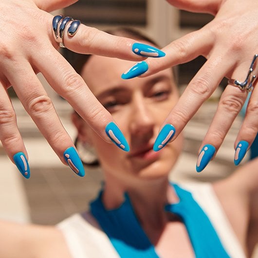 Model dressed in blue and white showing off a blue mani with pink details