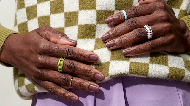Dark skin model wearing colorful clothing showing fingernails painted in a neutral skin tone shade