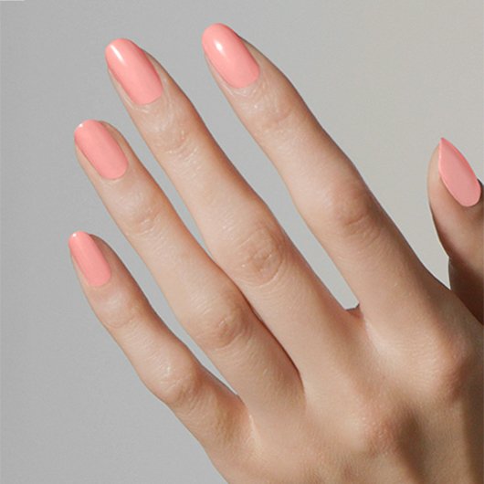 Light skin hand on gray background, nails painted in soft pink no prince needed essie nail polish