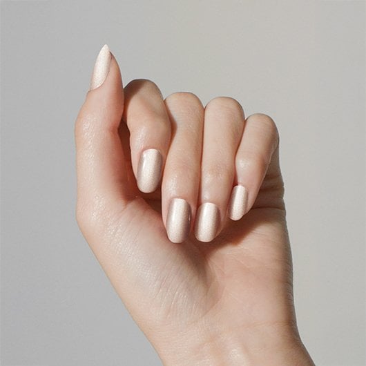 Light skin hand wearing reclaim the mirror silver nail polish with warm copper undertone